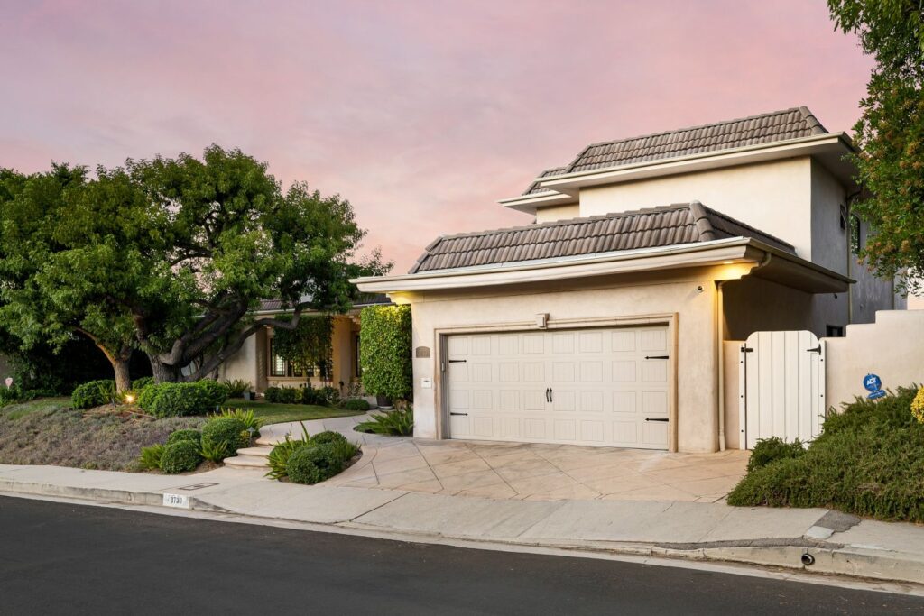 Modern garage door in a residential setting, surrounded by greenery and a well-maintained pathway, emphasizing curb appeal and architectural harmony.