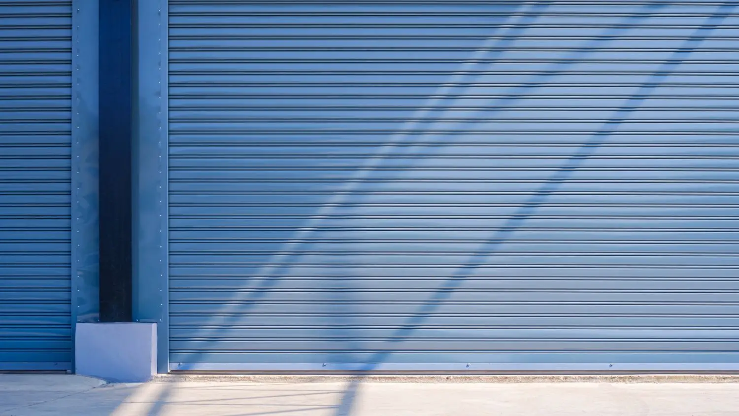 Garage door with horizontal slats and shadows, relevant to garage door spring repair and maintenance for homeowners in Katy, Texas.